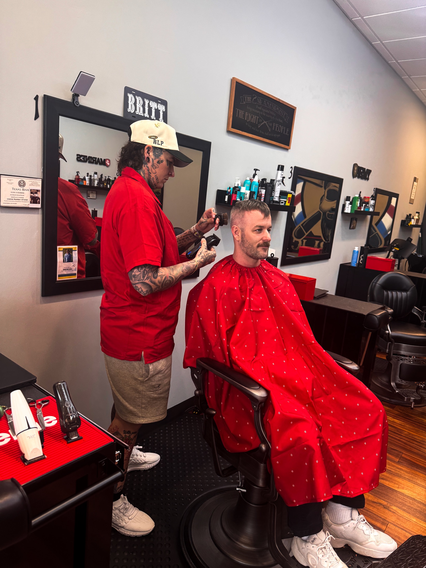 Brittany Parker cutting a client in the red Razor Republic cape