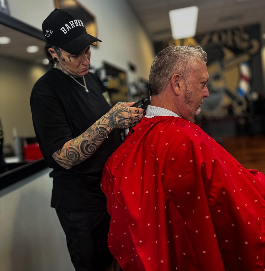 Brittany Parker cutting a client's hair in the coral cape